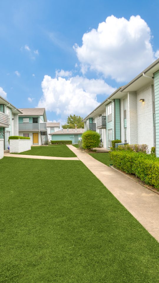 apartment complex with lawn and grass in front at The Las Ventanas