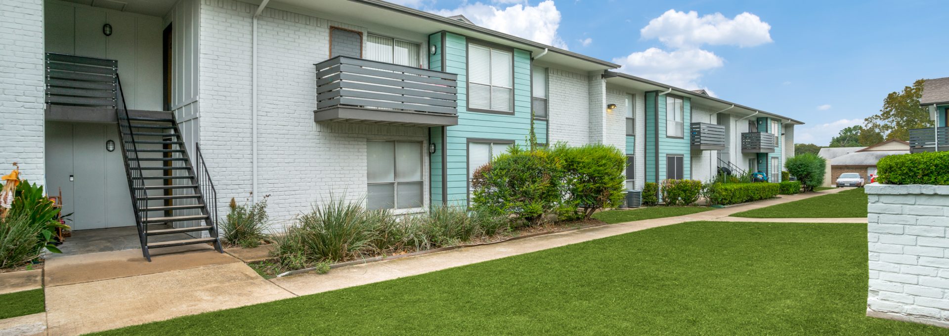 apartment complex with grass and trees in front at The Las Ventanas